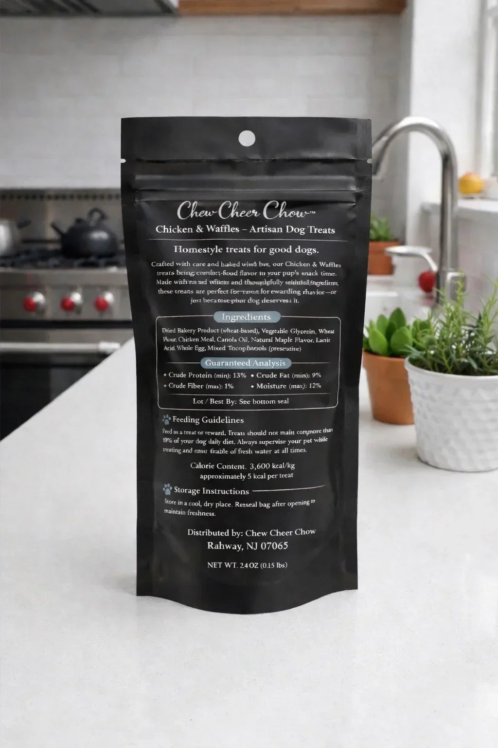 Chicken and waffles artisan dog treats packaging on a kitchen countertop with plants in background.